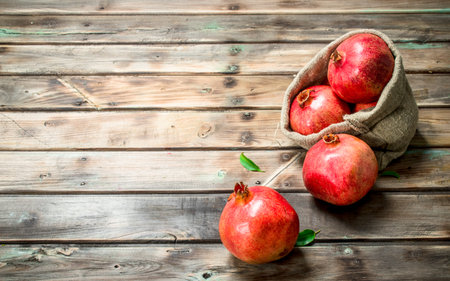 Fresh pomegranates in the sack. On wooden backgroundの写真素材