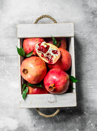 Fresh pomegranate in the box. On white rustic backgroundの写真素材