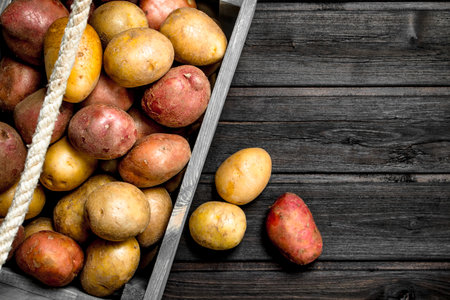 Potatoes in a box. On wooden backgroundの写真素材