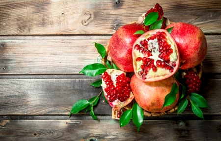 Fresh pomegranates with leaves in a basket. On wooden backgroundの写真素材