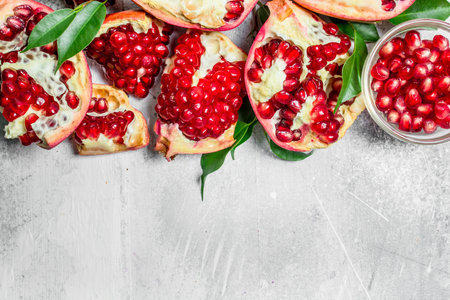 Pomegranate seeds with leaves. On rustic backgroundの写真素材