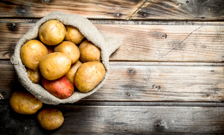 Potatoes in the sack. On wooden backgroundの写真素材