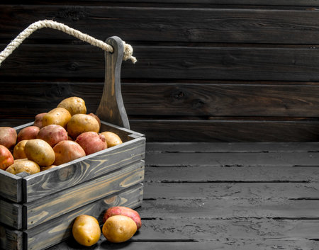 Fresh potatoes in a wooden box. On wooden backgroundの写真素材