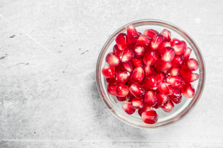 Pomegranate seeds in glass bowl. On rustic backgroundの写真素材
