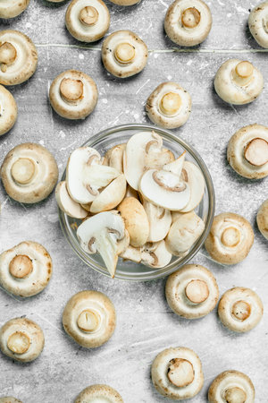 Pieces of fresh mushrooms in the bowl and whole mushrooms. On rustic backgroundの写真素材