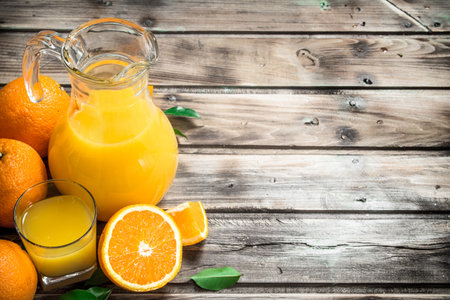 Orange juice in the pitcher. On wooden backgroundの写真素材