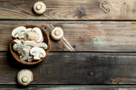 Pieces of fresh mushrooms in a bowl. On wooden backgroundの写真素材