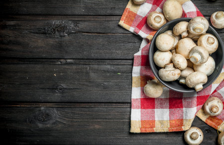 Ripe mushrooms in bowl on napkin. On wooden backgroundの写真素材
