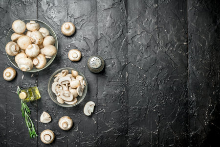 Fresh mushrooms in a bowl, bottled oil and pepper. On rustic backgroundの写真素材