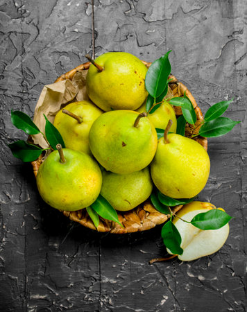 Fresh pears with leaves in basket. On black rustic backgroundの写真素材