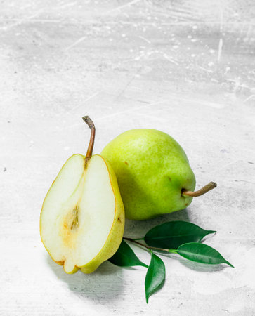 Half a fresh pear with leaves. On white rustic backgroundの写真素材
