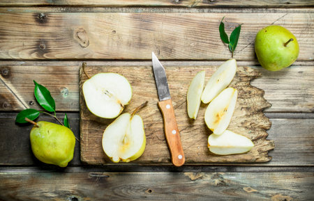 Pieces of pear on the cutting Board with a knife. On wooden backgroundの写真素材