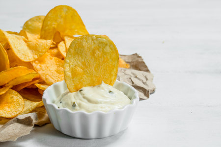 Potato chips in sauce. On white rustic background.の写真素材