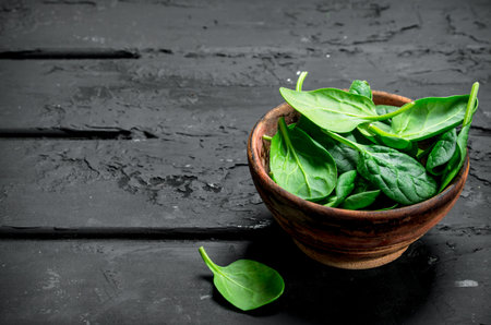 Spinach is in the bowl. On black rustic backgroundの写真素材