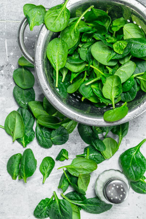Fresh spinach in a sauce pan and salt. On white rustic backgroundの写真素材