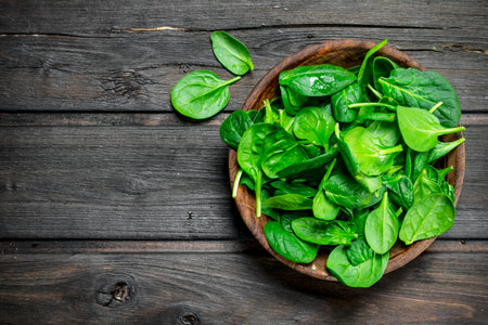 Spinach leaves in a bowl. On wooden backgroundの写真素材
