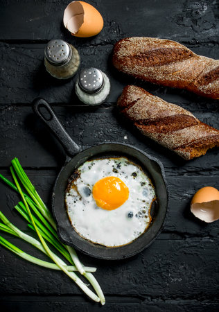 Fried egg with rye bread and spices. On black rustic background.の写真素材