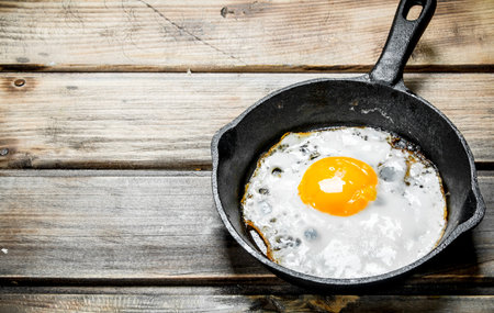 Fried egg in a frying pan. On a wooden background.の写真素材