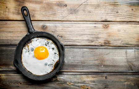 Fried egg in a frying pan. On a wooden background.の写真素材