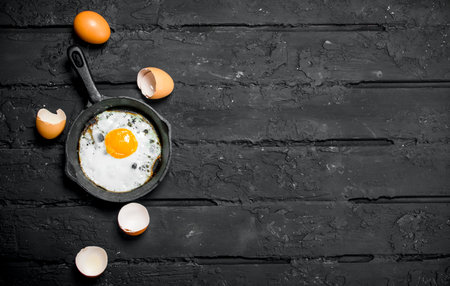 Fried egg in a frying pan. On black rustic background.の写真素材