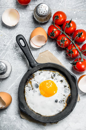 Fried egg with tomatoes. On a rustic background.の写真素材