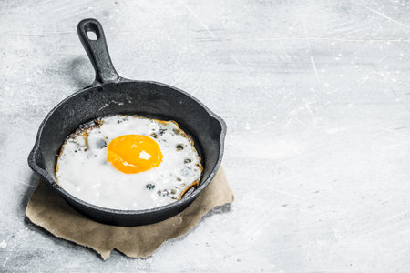 Fried egg in a frying pan. On a rustic background.の写真素材