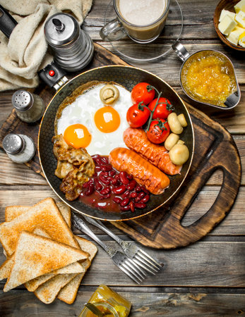English breakfast. Fried eggs with sausages, fried bread and aromatic coffee. On a wooden background.の写真素材