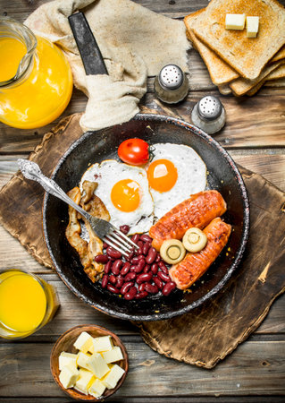 traditional English breakfast. Appetizers with fried bread and orange juice. On a wooden background.の写真素材