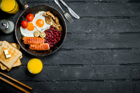 Traditional English Breakfast with orange juice. On black rustic background.の写真素材