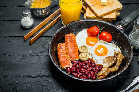 Traditional English Breakfast with orange juice. On black rustic background.の写真素材
