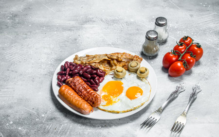 English breakfast. Fried eggs with sausages, bacon and beans. On a rustic background.の写真素材