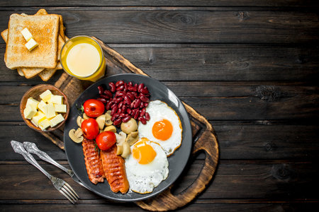 Traditional English Breakfast with fried eggs, sausages and beans. On a wooden background.の写真素材