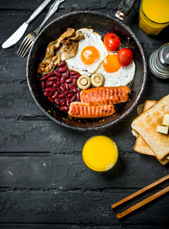 Traditional English Breakfast with orange juice. On black rustic background.の写真素材