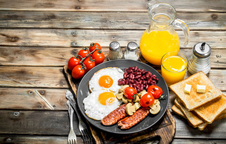 Traditional English breakfast. Fried eggs with beans, sausages and fried bread. On a wooden background.の写真素材