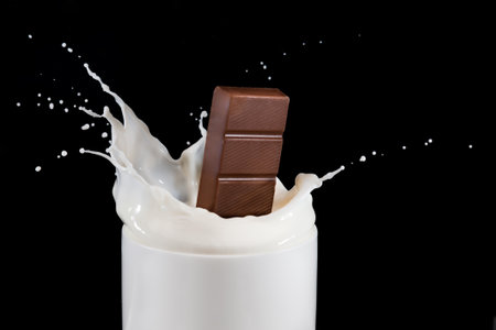 Chocolate falling and splashing in cup of milk