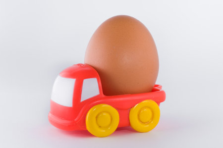 red toy truck loaded with an egg on white backgroundの写真素材