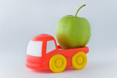 red toy truck loaded with an apple on a white backgroundの写真素材