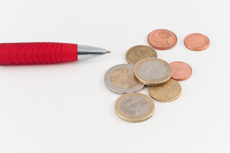 Red pen and coins on white background
