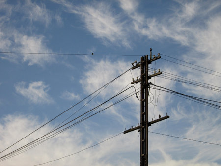 Power lines and electricity pylon against blue skyの写真素材