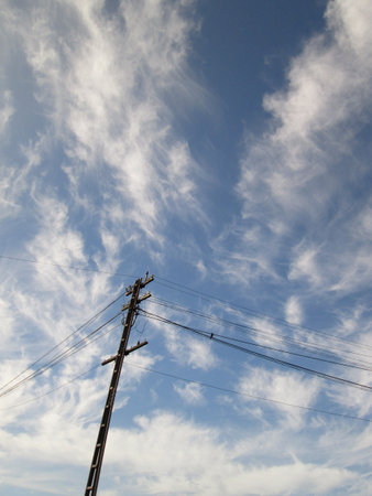 Electricity pylon against blue cloudy skyの写真素材