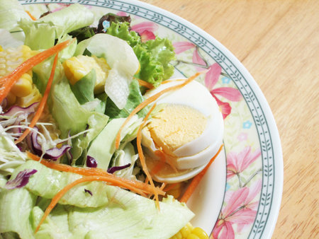 salad with vegetables and greens on wooden tableの写真素材