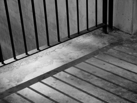 A closeup of view of a jail cells iron bars casting shadows on the prison floor with copy spaceの写真素材