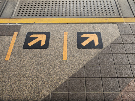 The Sign of yellow arrow on floor at train station