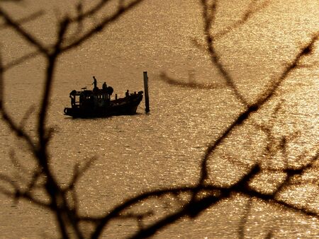 Silhouette man fishing in the sea with light sunsetの写真素材