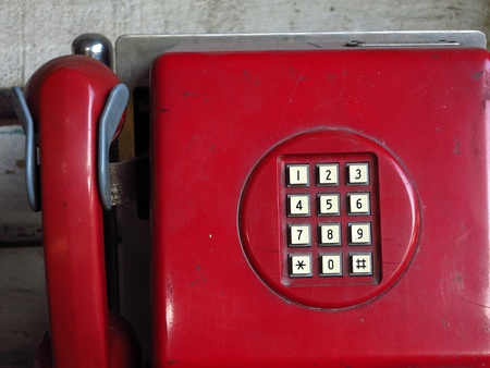 Old red phone hanging on the wall closeup