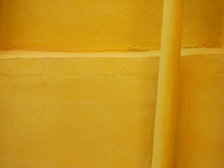 old yellow wall with pipeの写真素材