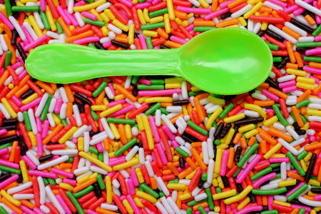 green plastic spoon on colorful sugar sprinkles