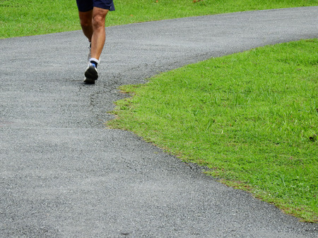 man jogging on the asphalt road in the parkの写真素材
