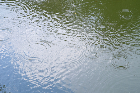 ripple of rain drop on water with reflectionの写真素材