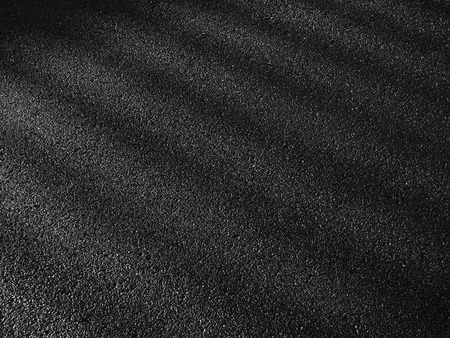 wet asphalt road with dark shadow of fence and light of morningの写真素材